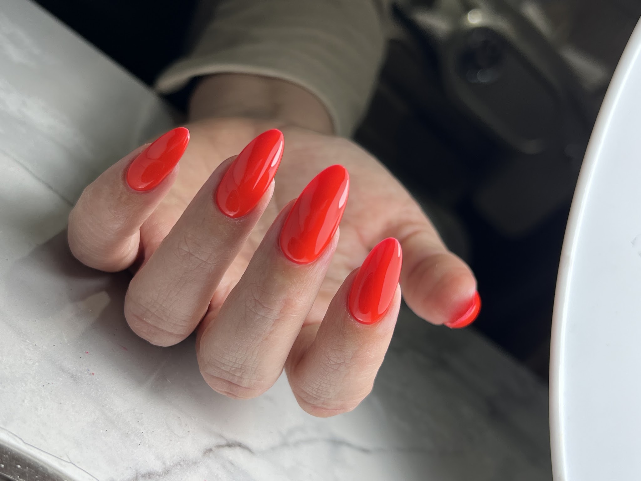 Rode almondnagels op een grijs marmeren tafeltje